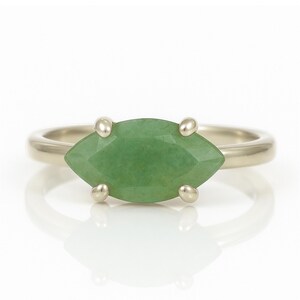 May include: A silver ring with a marquise-shaped green gemstone set in a prong setting.