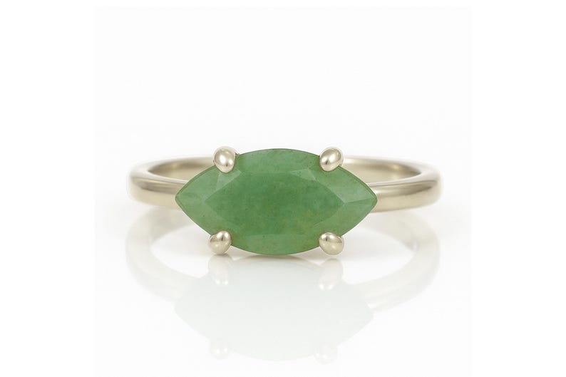 May include: A silver ring with a marquise-shaped green gemstone set in a prong setting.