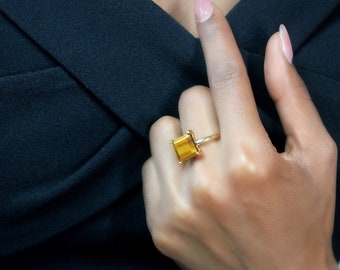Op de afbeelding: Een gouden ring met een vierkante tijgeroog-edelsteen.