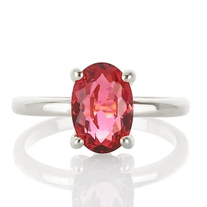 May include: A silver ring with a large oval-shaped pink gemstone.