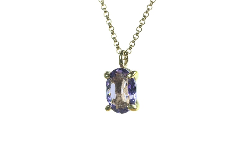 May include: A gold chain necklace with a purple oval gemstone pendant.