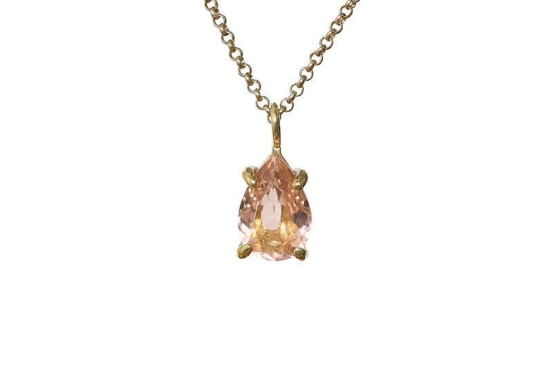 May include: A delicate gold chain necklace with a pear-shaped pink gemstone pendant.