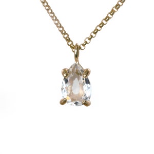 May include: A gold chain necklace with a pear-shaped clear crystal pendant.