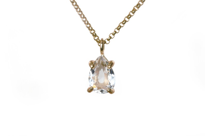 May include: A gold chain necklace with a pear-shaped clear crystal pendant.