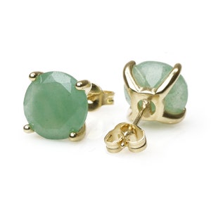 May include: A pair of gold earrings with green gemstone studs. The earrings have a simple design and are perfect for everyday wear.