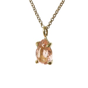May include: A gold chain necklace with a pear-shaped pink gemstone pendant.