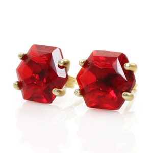 Könnte beinhalten: Ein Paar goldene Ohrringe mit roten sechseckigen Edelsteinen.