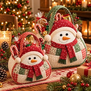May include: Two quilted fabric baskets shaped like snowmen with red and green patchwork patterns. Each snowman features a carrot nose, black eyes, a stitched smile, and a red scarf. The baskets are filled with wrapped candies and treats.