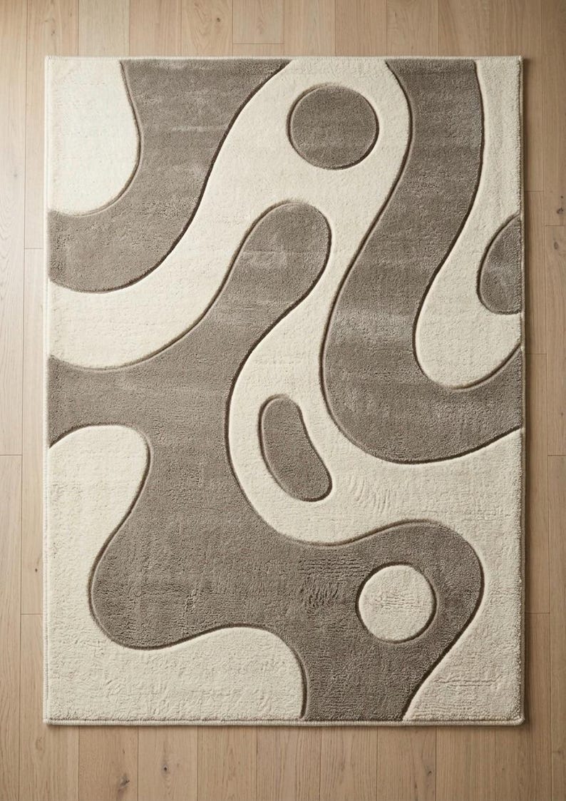 Pu&ograve; includere: Un tappeto rettangolare caratterizzato da una texture a pelo alto e basso con un design bicolore. Il motivo &egrave; composto da forme organiche fluide e cerchi color tortora su uno sfondo color crema, creando un effetto di rilievo e profondit&agrave;.