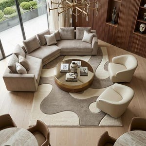 Pu&ograve; includere: Un soggiorno con un grande divano angolare beige, due poltrone color crema e un tavolino rotondo con piano a specchio. Un tappeto fantasia con forme organiche beige e marroni poggia sul pavimento in legno chiaro sotto un lampadario.