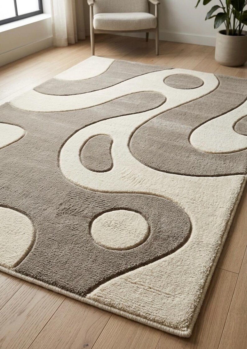 Pu&ograve; includere: Un tappeto rettangolare caratterizzato da una texture a pelo alto e basso con un design bicolore color crema e tortora. La superficie presenta un motivo astratto di linee curve fluide e forme circolari che creano un effetto in rilievo.