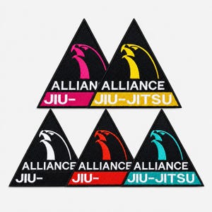 May include: Five triangular embroidered patches featuring a black background with a stylized eagle head logo. Each patch displays the text ALLIANCE JIU-JITSU in white, with colored accents in pink, yellow, white, red, and teal on the borders and text.