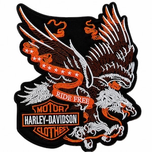 Puede incluir: Un parche bordado que presenta un águila grande con detalles en hilo marrón, blanco y naranja. Una cinta naranja con estrellas blancas y el texto RIDE FREE se curva sobre el águila. Debajo, un escudo negro muestra MOTOR HARLEY-DAVIDSON CLOTHES.