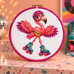May include: A cross-stitch embroidery in a circular pink hoop featuring a pink flamingo wearing a pink helmet, a yellow fanny pack, and teal roller skates with yellow stars and pink wheels, all set against a white fabric background.