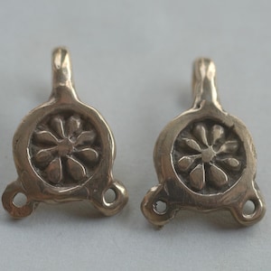 May include: Two antique bronze metal clasps with a flower design. Each clasp has three loops for attaching to fabric.