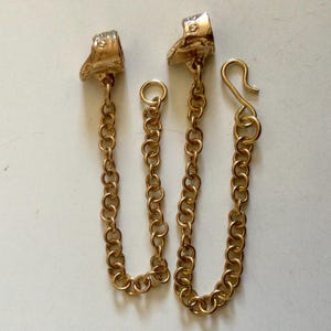 May include: Two gold-toned chain connectors with a hook on one end and a loop on the other. The connectors are designed to be used with a bracelet or necklace.