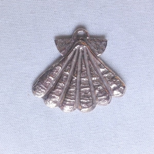 Peut inclure: Un pendentif en forme de coquille Saint-Jacques en argent. La coquille est détaillée avec des crêtes et une surface texturée.