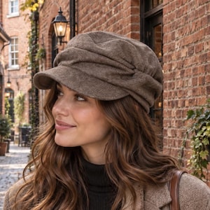 May include: A brown newsboy cap with a gathered, textured fabric design and a short, stiff brim. The cap features a soft, rounded crown with subtle pleats around the circumference, providing a structured yet relaxed appearance for headwear.