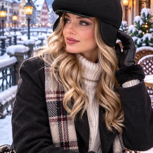 May include: A black wool flat cap with ear flaps, a cream-colored cable knit turtleneck sweater, a black wool coat with faux fur cuffs, a plaid scarf in shades of beige, black, and red, and black leather gloves.