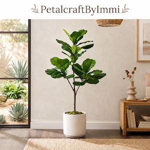 May include: A tall artificial fiddle leaf fig plant with large, dark green, violin-shaped leaves and a slender brown trunk. The plant is potted in a simple, cylindrical, off-white ceramic planter that sits directly on the floor.
