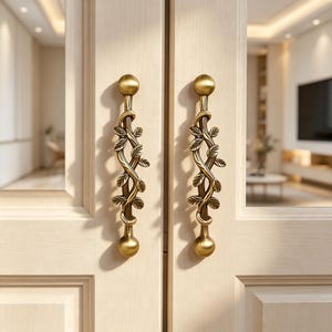 May include: Two vertical door handles made of antique brass-toned metal, featuring a central design of intertwined vines and leaves. Each handle has a smooth, spherical knob at the top and bottom, mounted onto a light-coloured wooden door frame.