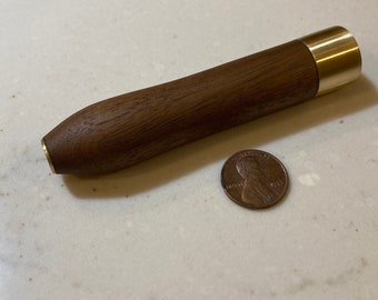 Könnte beinhalten: Ein Nudelholz aus Holz und Messing mit abgerundetem Ende. Das Nudelholz ist etwa so groß wie eine deutsche Ein-Cent-Münze.