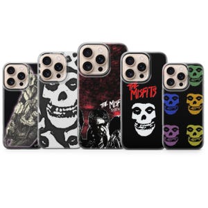 Pode incluir: Cinco capas para smartphone com imagens da banda The Misfits. Os designs incluem uma caveira em preto e branco, um gráfico de um membro da banda em vermelho e preto com texto, e uma capa preta com texto vermelho e uma caveira branca.