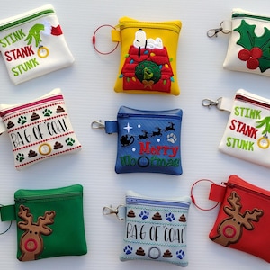 May include: Eight small zippered pouches with various Christmas-themed designs. The pouches are made of white, red, green, blue, and yellow fabric. The designs include a reindeer, a bag of coal, a Christmas tree, a snowman, and a Grinch-themed design. The pouches have a small loop for attaching a key ring.