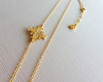 May include: A gold chain necklace with a detailed cross pendant. The chain has a peace sign charm at the end.