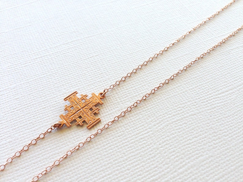 May include: A gold-toned necklace with a delicate chain and a detailed cross pendant.