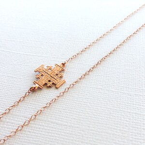 May include: A rose gold necklace with a delicate chain and a detailed cross pendant.