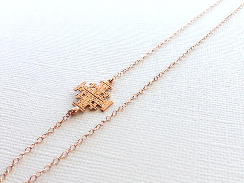 May include: A rose gold necklace with a delicate chain and a detailed cross pendant.