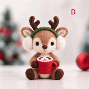 May include: A needle-felted brown deer figurine with dark brown antlers, wearing a green headband and white earmuffs. The deer holds a red mug filled with white marshmallows. The letter D is visible in the upper right corner of the image.