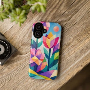 May include: A smartphone case featuring a vibrant, geometric floral pattern with stylised tulips and blossoms in shades of pink, yellow, blue, and green against a light blue sky background with a circular orange sun element at the top.