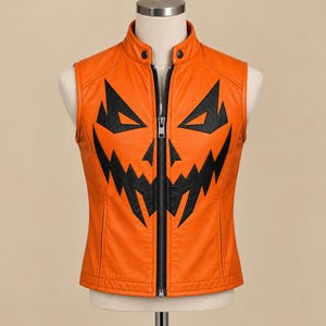 May include: A bright orange sleeveless vest featuring a black jack-o'-lantern face graphic across the front. The vest has a high collar with a snap button closure, a full-length black front zipper, and vertical seam detailing along the torso.