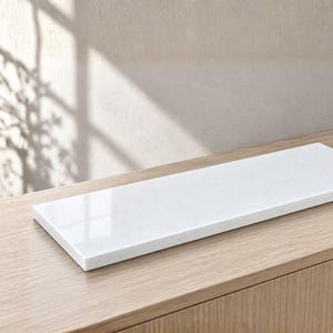 Könnte beinhalten: Ein rechteckiges weißes Regal mit einer glatten, glänzenden Oberfläche und sauberen, geraden Kanten. Das Regal ist flach und massiv und weist eine gleichmäßige weiße Oberfläche auf, die Licht reflektiert und ein schlichtes, funktionales Design bietet.