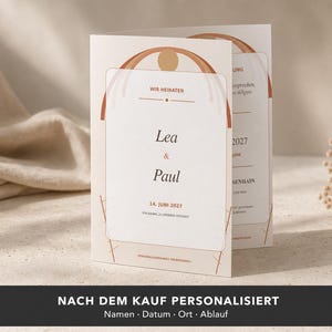 Puede incluir: Una tarjeta de invitación de boda plegada con fondo color crema, gráficos de arco en tonos terracota y un círculo central. El texto dice "WIR HEIRATEN", "Lea & Paul" y "14. JUNI 2027" en una fuente serif oscura.