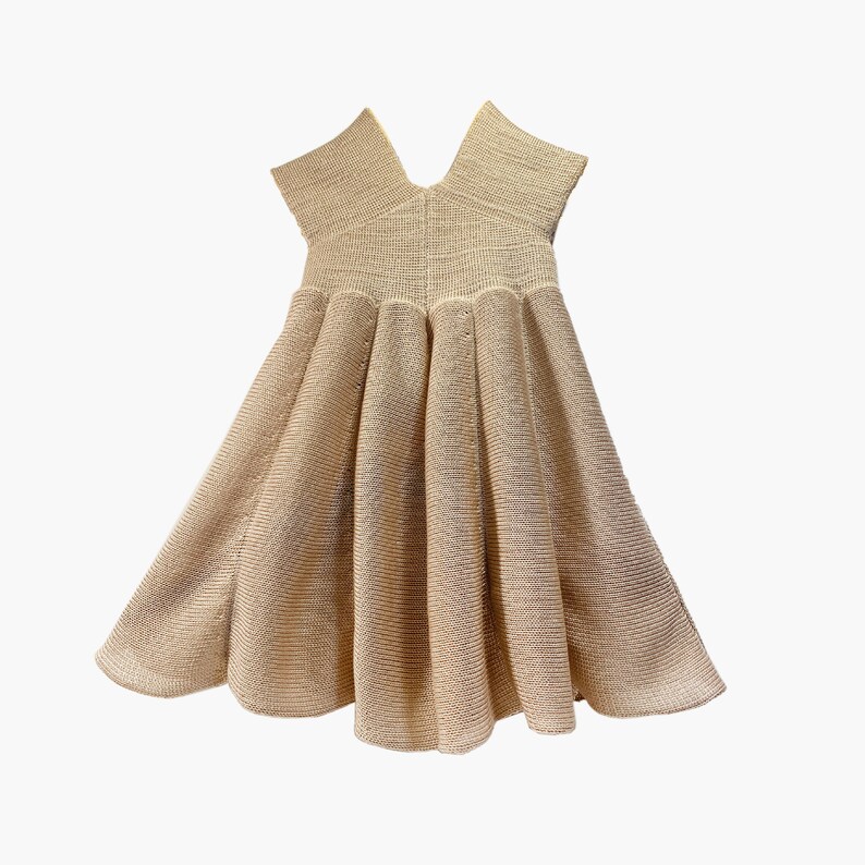 May include: A beige sleeveless dress with a V-neck and a pleated skirt.