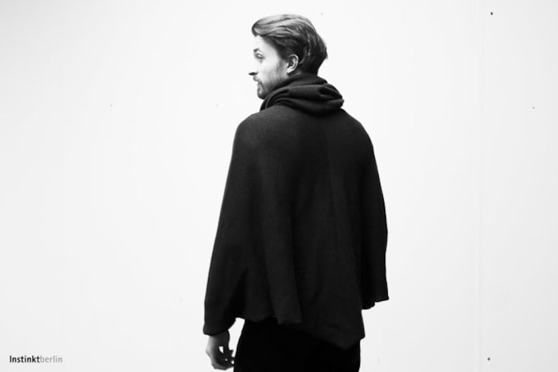 May include: A black hooded poncho with a long, flowing design. The poncho is made of a soft, comfortable fabric and has a relaxed fit.