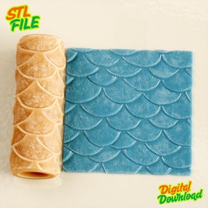 Puede incluir: Un rodillo cilíndrico de color tostado con un patrón de escamas de pez en relieve junto a un cuadrado de material azul grabado con el mismo diseño de escamas. La imagen incluye el texto STL FILE y Digital Download en verde.