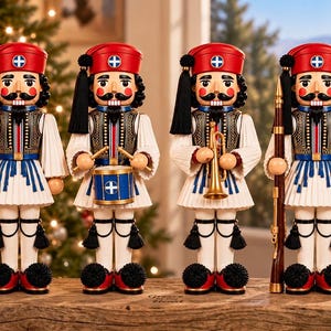 May include: Four wooden nutcrackers dressed in traditional Greek Evzone uniforms, featuring red caps with blue and white emblems, white pleated kilts, black vests, and black pom-pom shoes. They hold a Greek flag, a drum, a trumpet, and a rifle.