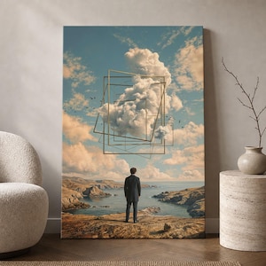 May include: A rectangular wall art print depicting a person in a dark suit standing on a rocky cliff overlooking a calm sea. Above, a large white cloud is framed by several thin, intersecting gold-coloured geometric square wire frames.