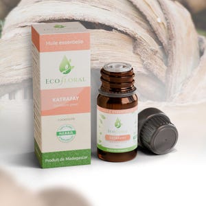 Peut inclure: Un flacon en verre brun d'huile essentielle de Katrafay avec un bouchon noir et sa boîte en carton rectangulaire assortie. L'étiquette et la boîte portent le logo EcoFloral, le texte Katrafay, Cedrelopsis grevei et Produit de Madagascar.