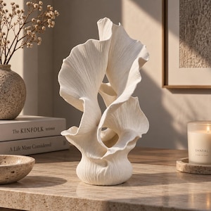 Può includere: Una scultura in ceramica bianca caratterizzata da forme organiche e fluide a ventaglio con una superficie testurizzata e a coste. L'oggetto si erge con molteplici strati curvi a forma di petalo che creano una struttura complessa e stratificata.