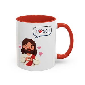 May include: A white ceramic mug with a red interior and handle, featuring a pixel art illustration of a figure with brown hair and a beard wearing a white robe with a red sash, making a heart shape with hands, surrounded by pink hearts.