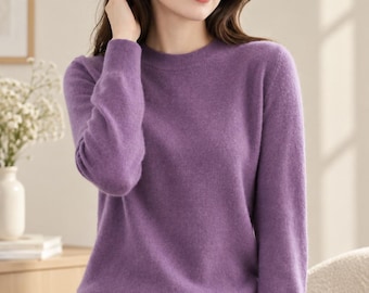 May include: A long-sleeved, crew-neck jumper in a solid purple hue. The garment features a ribbed knit texture at the collar, cuffs, and hemline, providing a structured fit. The fabric appears soft and lightweight, with a consistent colour throughout.