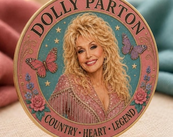 May include: A circular decorative plaque featuring a portrait of Dolly Parton with blonde hair, wearing a pink fringed garment. The design includes pink borders, butterflies, roses, and stars, with the text DOLLY PARTON and COUNTRY HEART LEGEND.