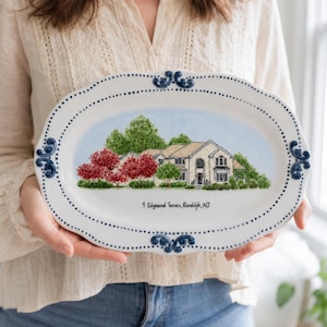 May include: An oval ceramic serving platter with a white base, blue dotted border, and blue scroll accents. The centre features a hand-painted illustration of a house with red and green trees. The text 9 Edgewood Terrace, Randolph, NJ is printed.