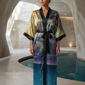 May include: A long-length robe featuring a vibrant, painterly landscape print in shades of blue, green, and gold. The garment includes wide sleeves, a solid black satin trim along the front opening, and a matching black satin tie belt at the waist.