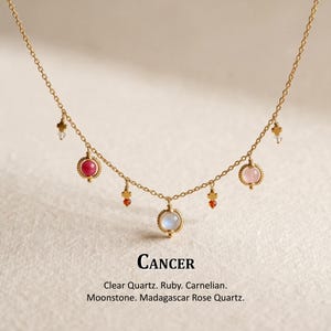 May include: A gold chain necklace featuring multiple dangling charms, including round clear quartz, ruby, carnelian, moonstone, and Madagascar rose quartz beads. The text below reads: Cancer. Clear Quartz. Ruby. Carnelian. Moonstone. Madagascar Rose Quartz.